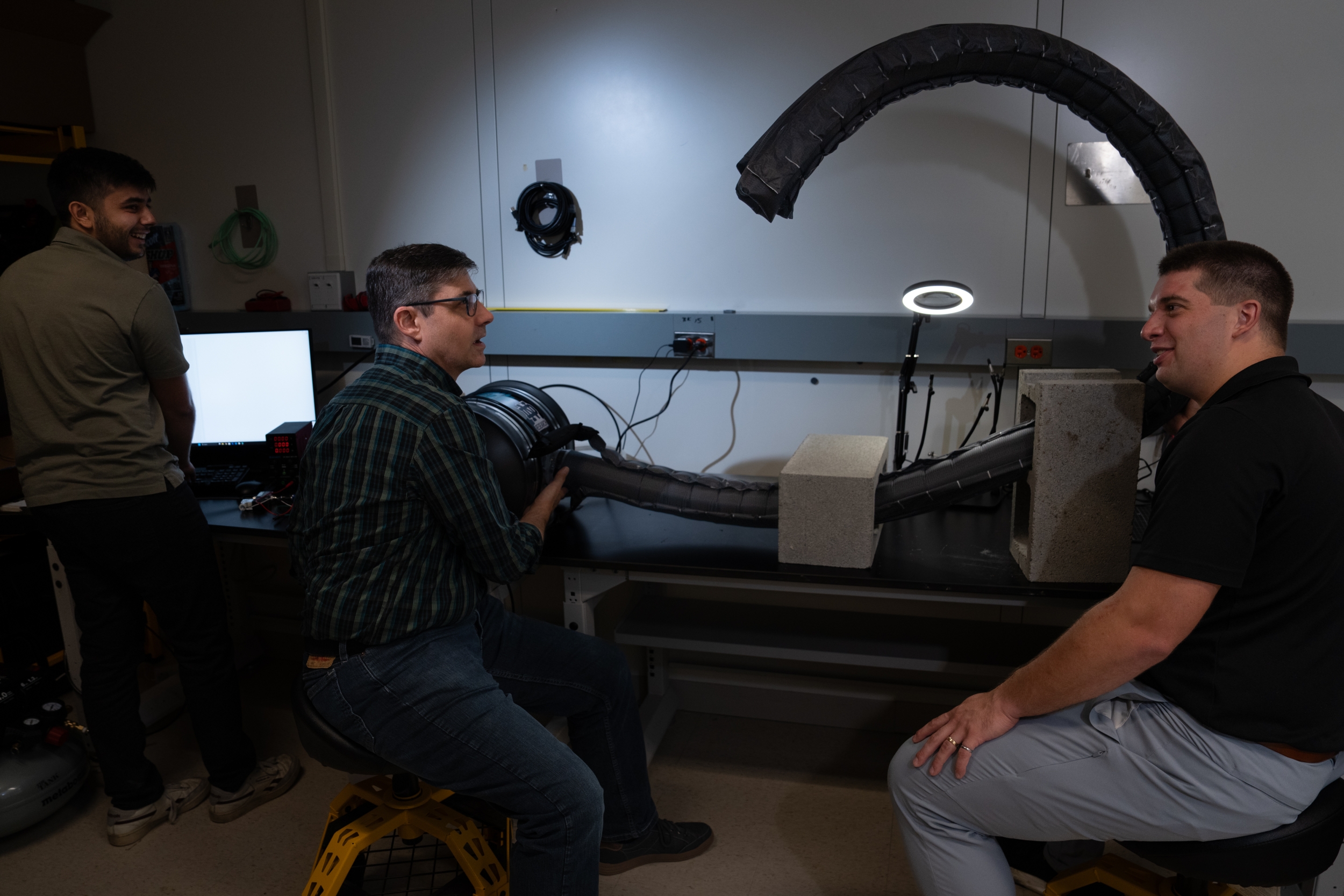 Three project team members test the robot's flexibility in an indoor laboratory setting.