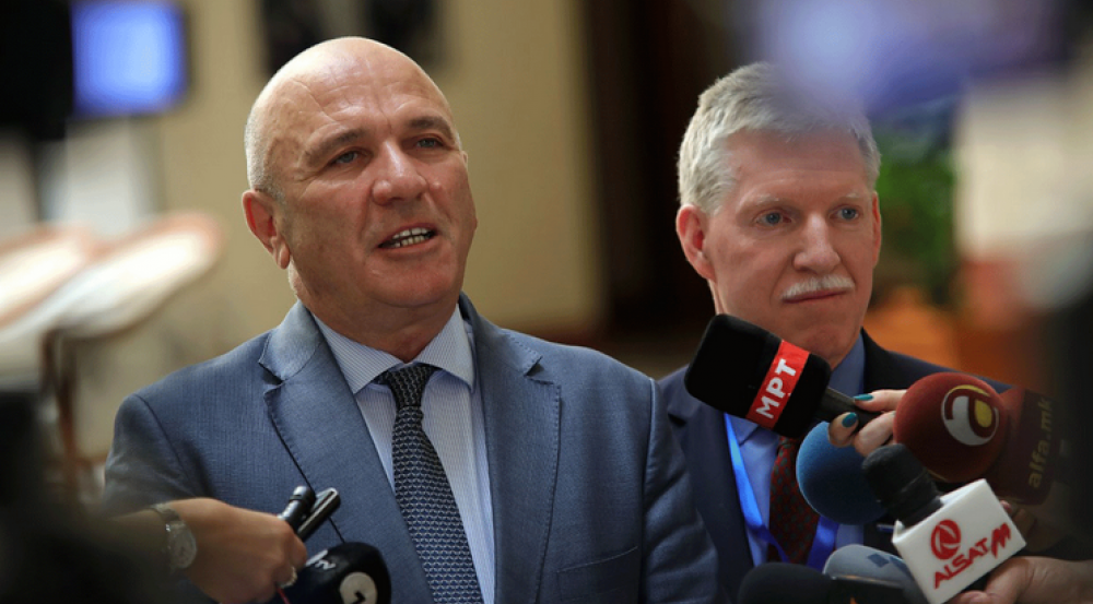 Photo of two men talking into microphones at a press conference